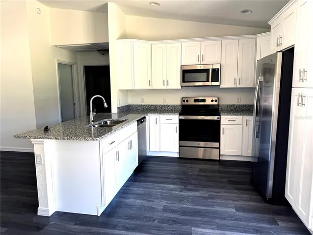 a kitchen with stainless steel appliances kitchen island granite countertop a stove a sink and a refrigerator