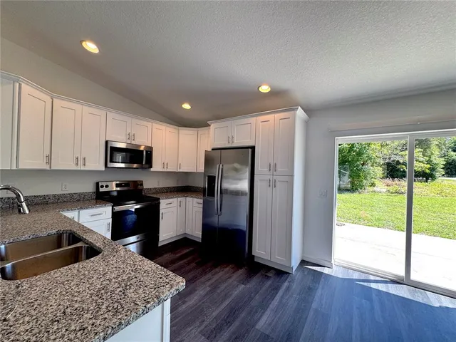 a kitchen with stainless steel appliances granite countertop a refrigerator stove top oven and sink