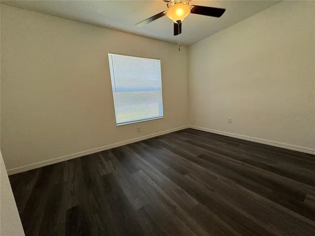 an empty room with wooden floor chandelier and window