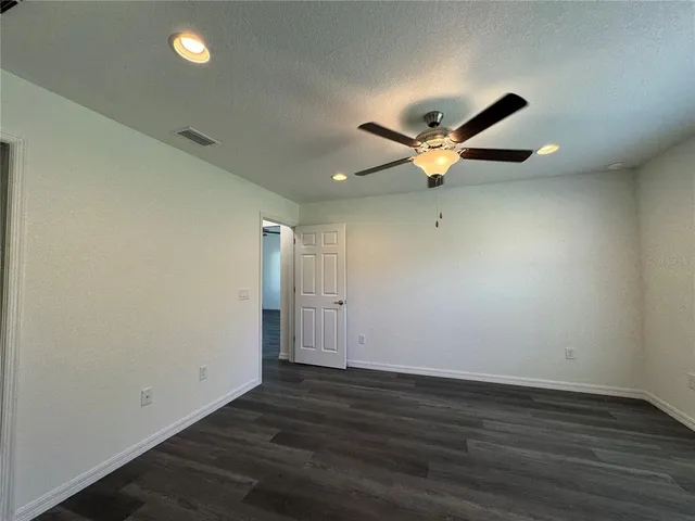 an empty room with wooden floor and ceiling fan