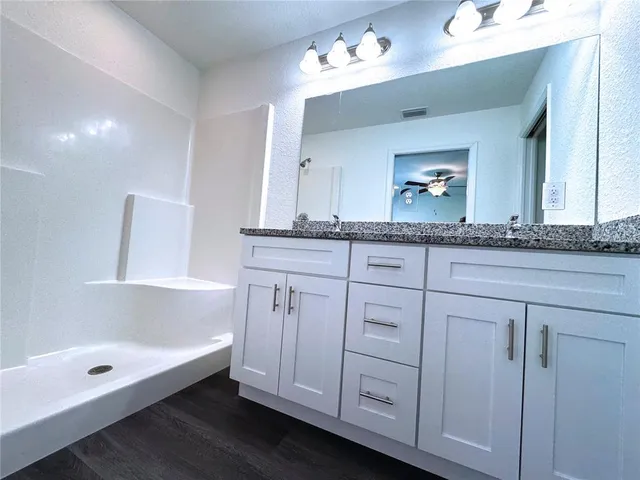 a bathroom with a granite countertop sink two mirror and bathtub