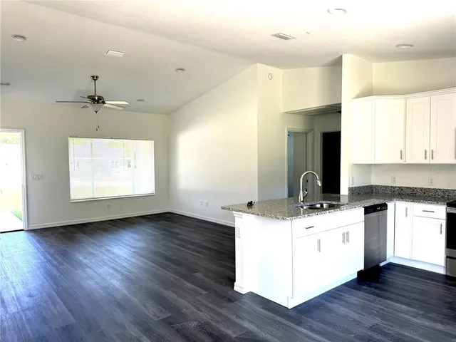 a kitchen with a stove and white cabinets with wooden floor