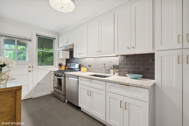 a kitchen with white cabinets appliances and a window
