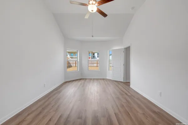 an empty room with wooden floor chandelier fan and windows