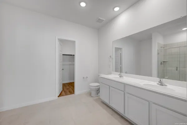 a spacious bathroom with a granite countertop sink a toilet and a mirror