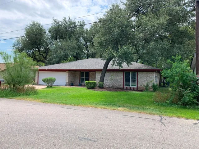 a front view of a house with a yard and trees