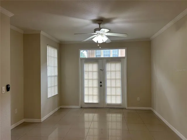 an empty room with chandelier fan and windows