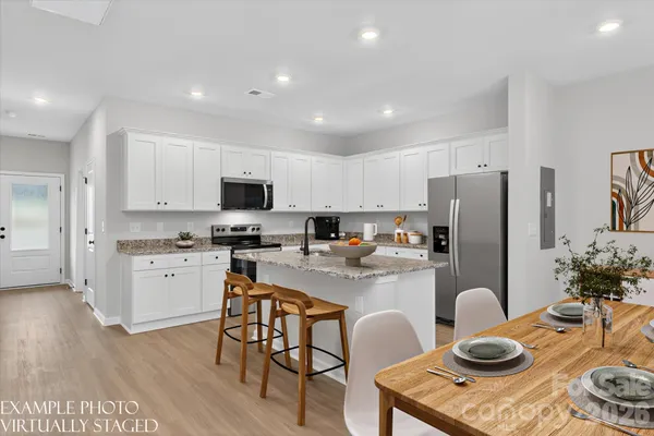 a kitchen with stainless steel appliances granite countertop a refrigerator a stove a sink and a dining table with wooden floor