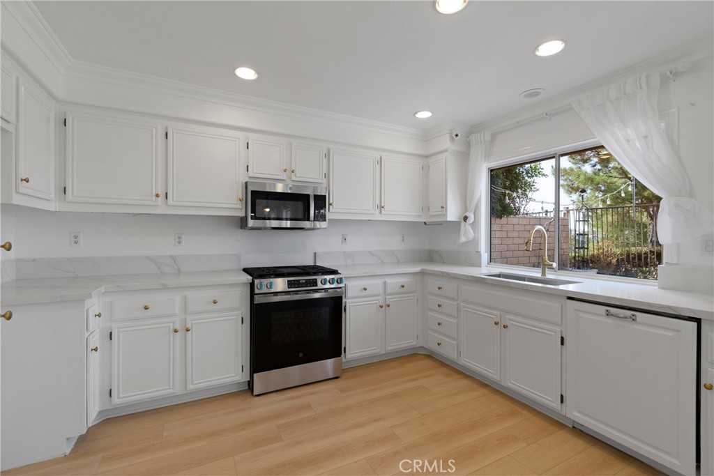 22 Carriage Drive Lake Forest, CA 92610 - Photo 9 of 35 a kitchen with granite countertop white cabinets a sink a window and stainless steel appliances