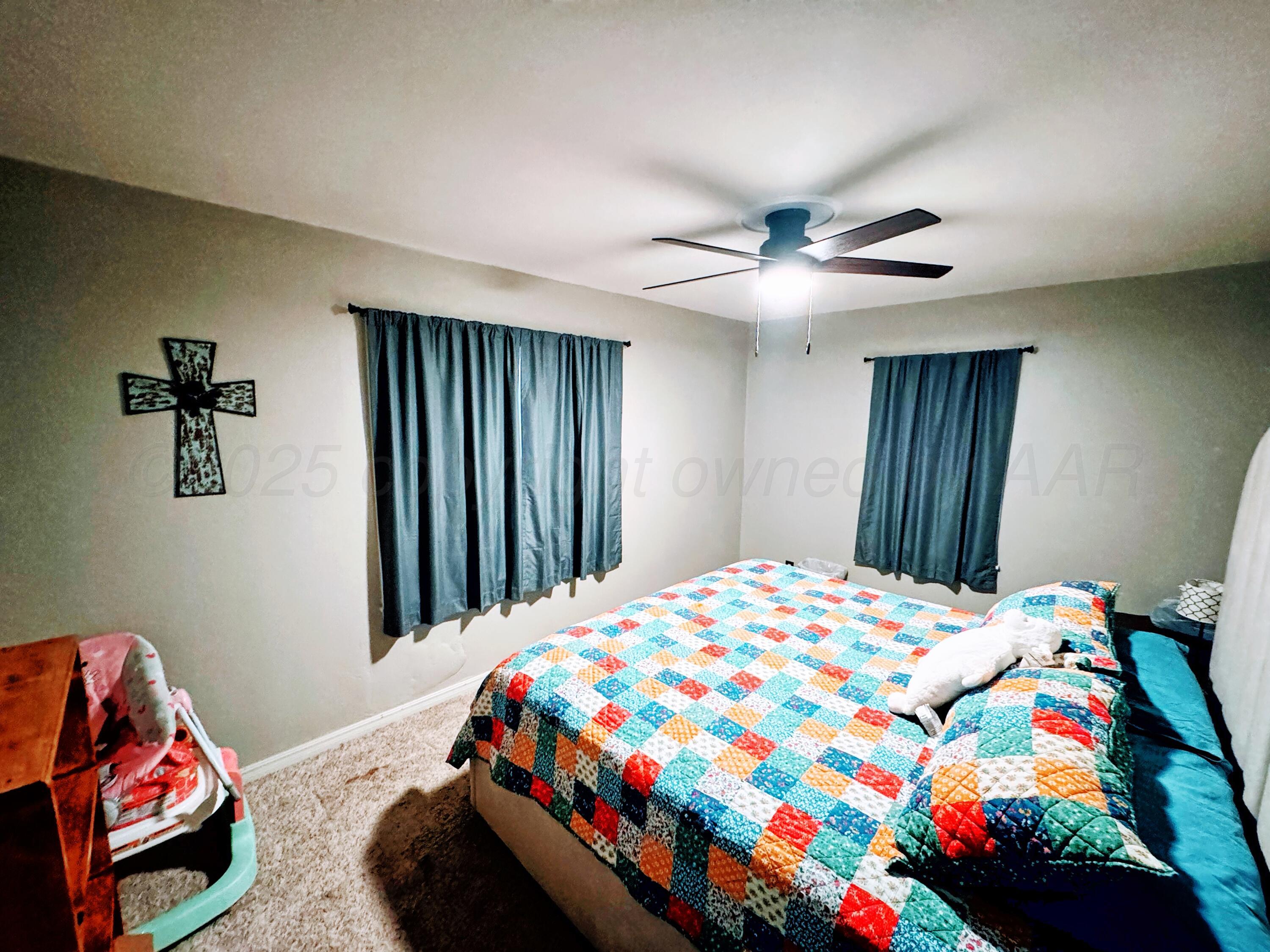 14490 County Road 24 Perryton, TX 79070 - Photo 11 of 28 a bedroom with a bed and a chandelier