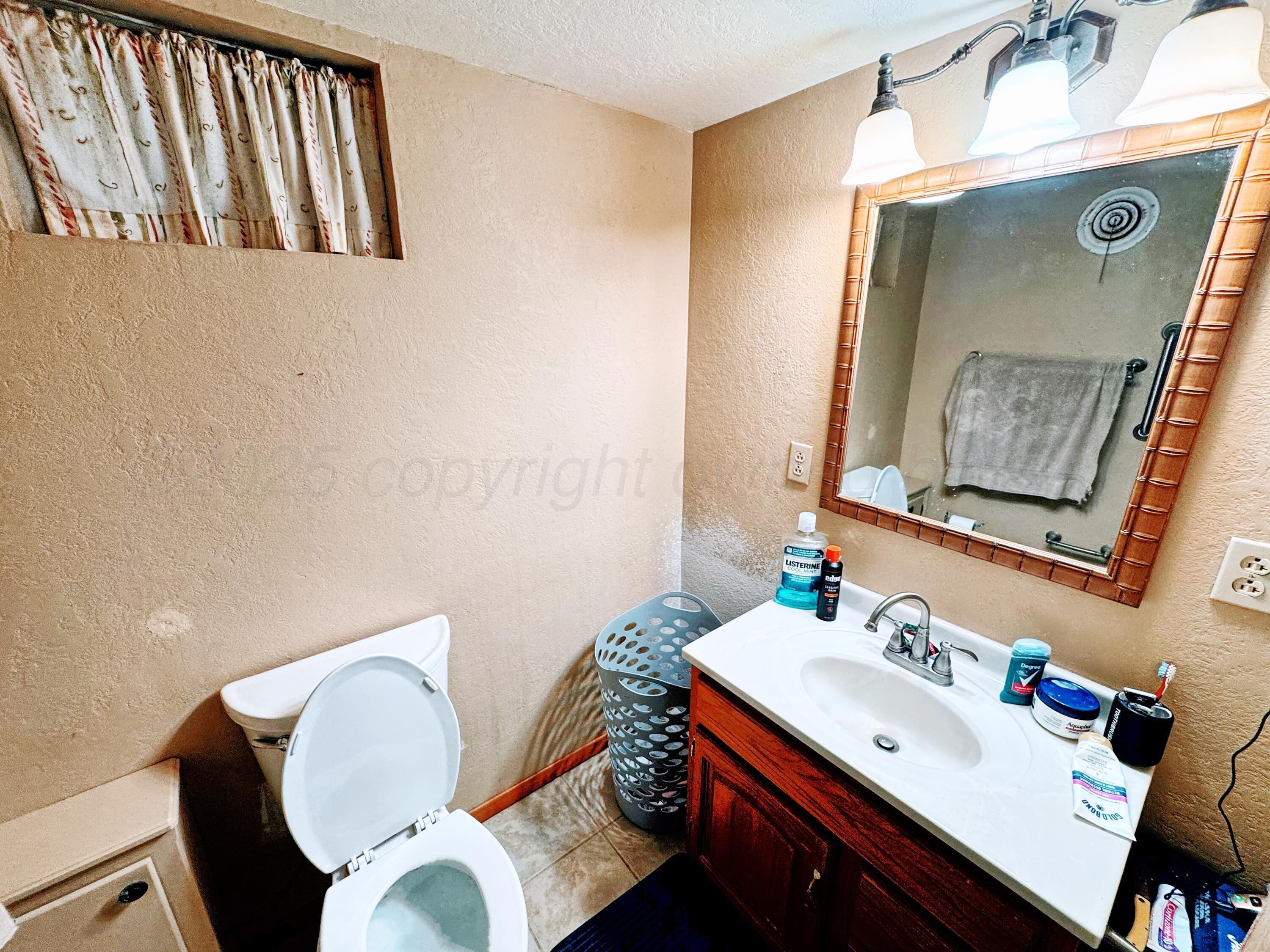 14490 County Road 24 Perryton, TX 79070 - Photo 17 of 28 a bathroom with a sink mirror and toilet