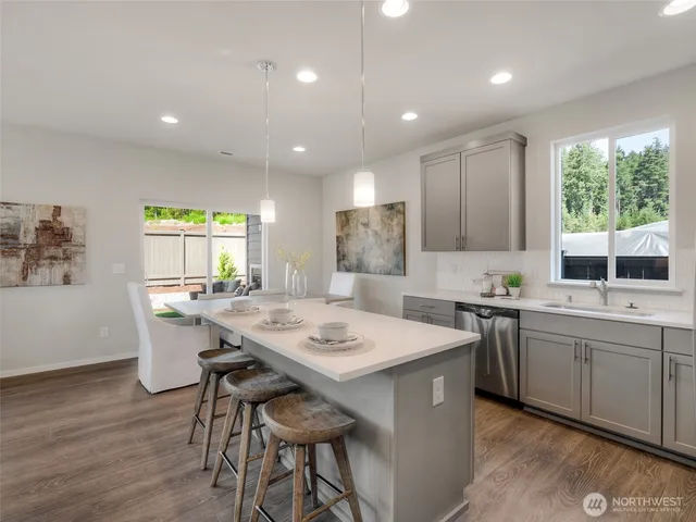 a kitchen with stainless steel appliances granite countertop a sink a stove a dining table and chairs