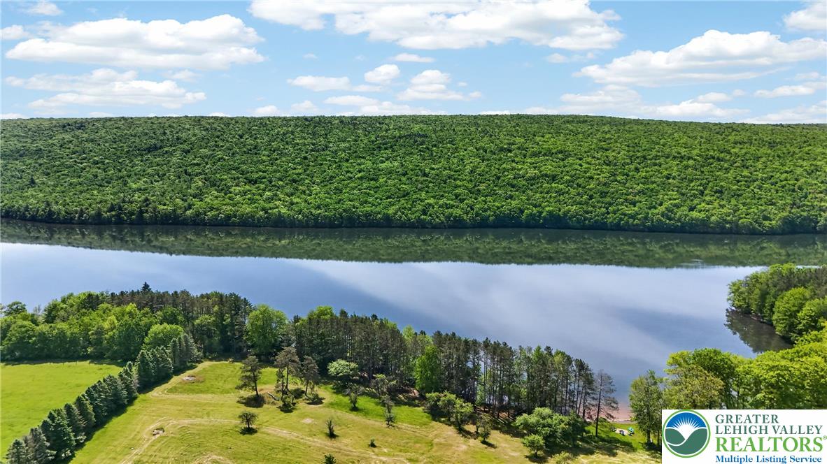 Ben Titus Road Tamaqua, PA 18252 - Photo 7 of 7 A tranquil lake reflects the verdant hillside under a clear sky.