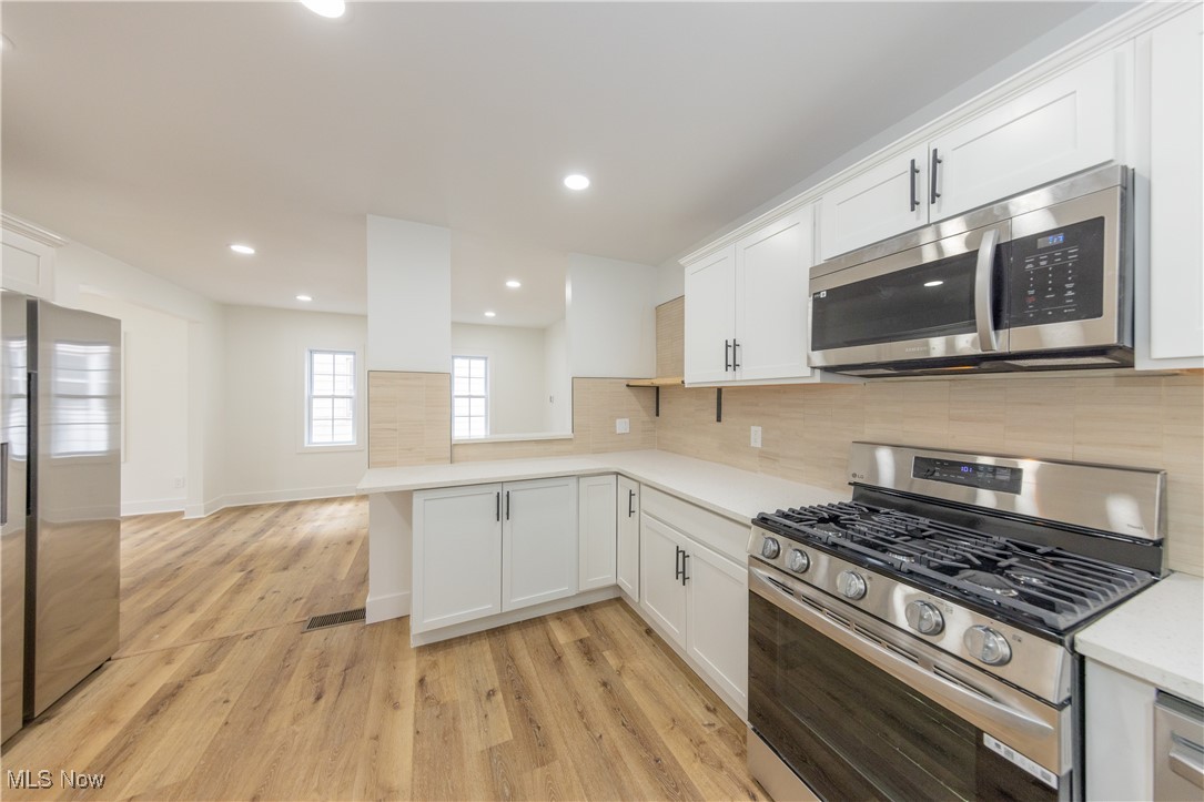 3694 Chelton Road Cleveland, OH 44120 - Photo 12 of 33 Kitchen featuring white cabinetry, light countertops, appliances with stainless steel finishes, and light wood-type flooring