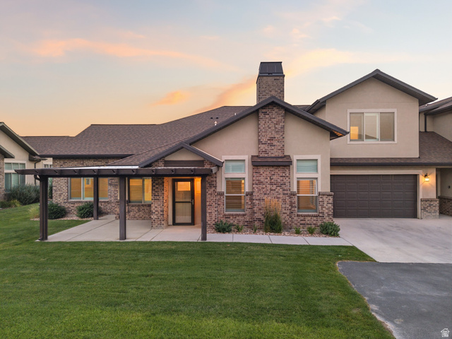1809 West 200 North, Unit C Mapleton, UT 84664 - Photo 1 of 1 Exterior featuring a two-car garage, brick facade with stucco accents, pergola-covered patio, paved driveway, and established landscaping