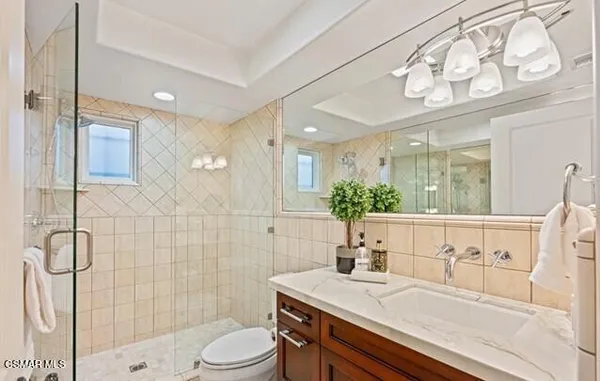 a bathroom with a sink a toilet a mirror and shower