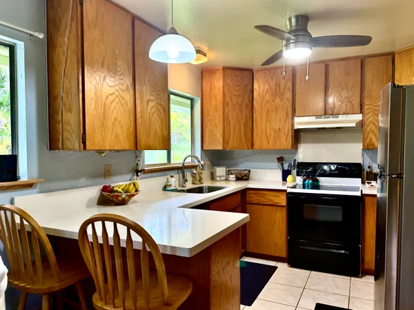 a kitchen with a sink a stove a chandelier cabinetry and chairs