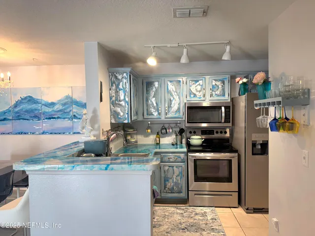 a kitchen with stainless steel appliances kitchen island granite countertop a stove top oven a sink a counter space and cabinets