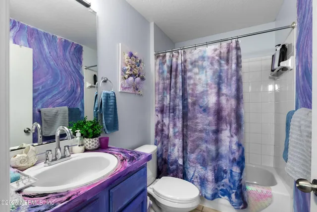 a bathroom with a sink a toilet and shower curtain