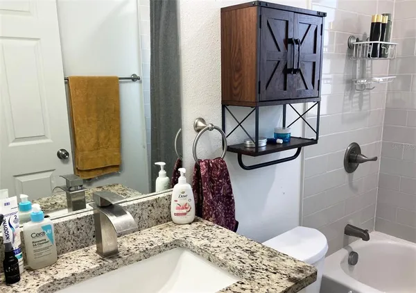 a bathroom with a granite countertop sink a toilet and bathtub