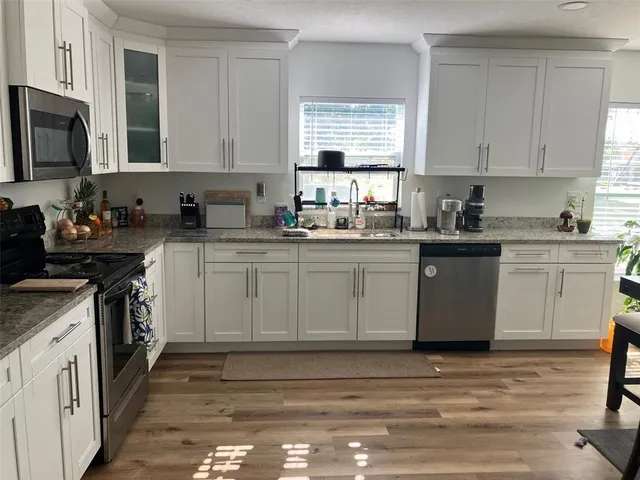 a kitchen with a sink cabinets appliances and a window