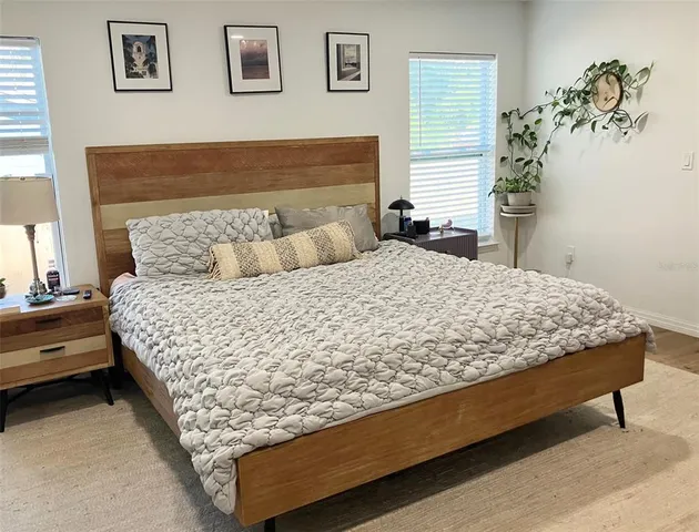 a large bed sitting in a bedroom next to a window with potted plant