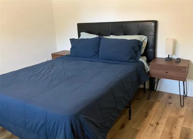 a bed sitting in a bedroom next to a window with wooden floor