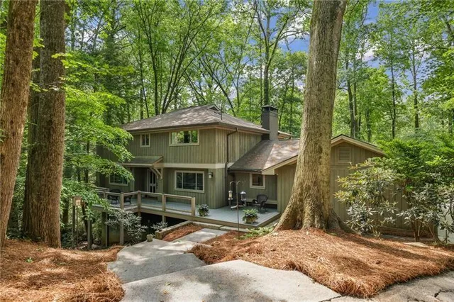 a view of a barn with large trees and a wooden fence