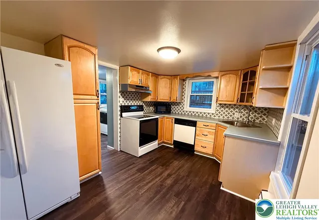a kitchen with granite countertop a refrigerator a sink dishwasher stove and oven