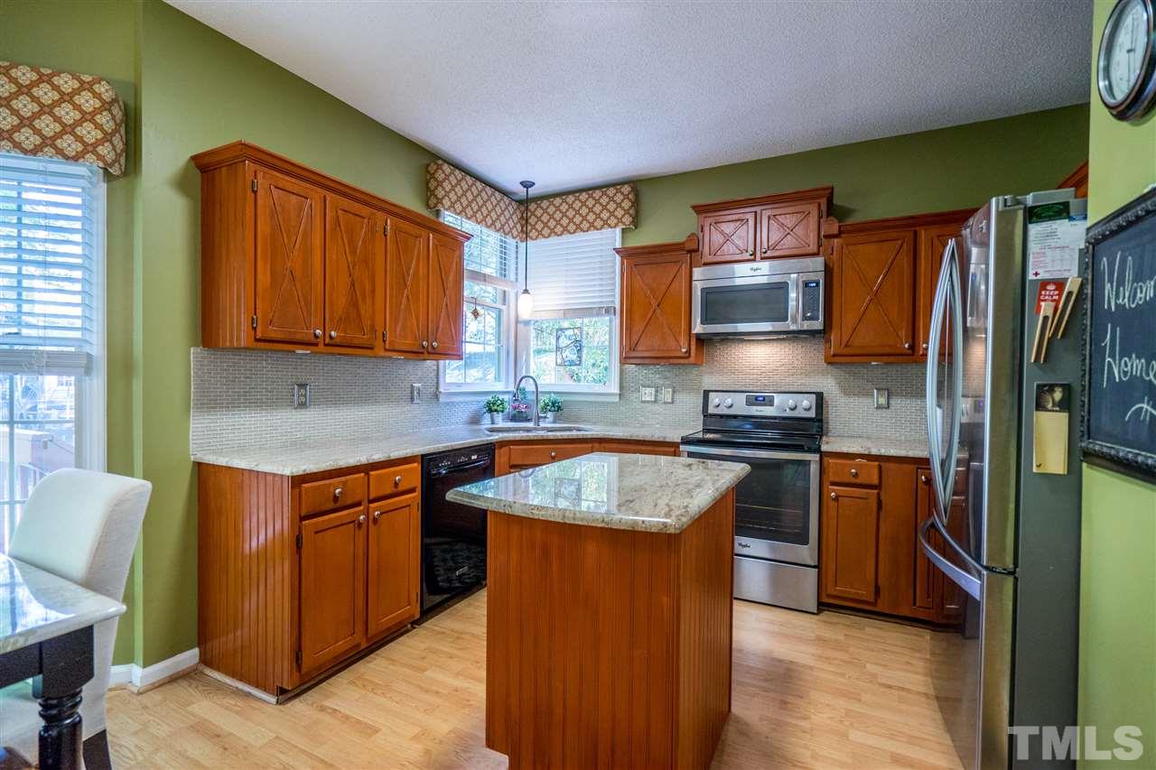 11912 Fairlie Place Raleigh, NC 27613 - Photo 11 of 25 a kitchen with stainless steel appliances granite countertop sink stove top oven and refrigerator