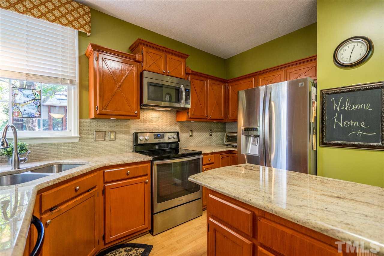 11912 Fairlie Place Raleigh, NC 27613 - Photo 12 of 25 a kitchen with stainless steel appliances granite countertop a sink refrigerator stove microwave and cabinets