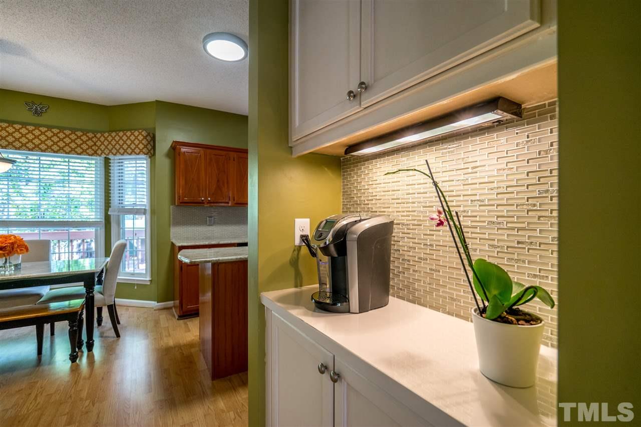 11912 Fairlie Place Raleigh, NC 27613 - Photo 15 of 25 a kitchen with a potted plant on the granite counter tops and a view of living room