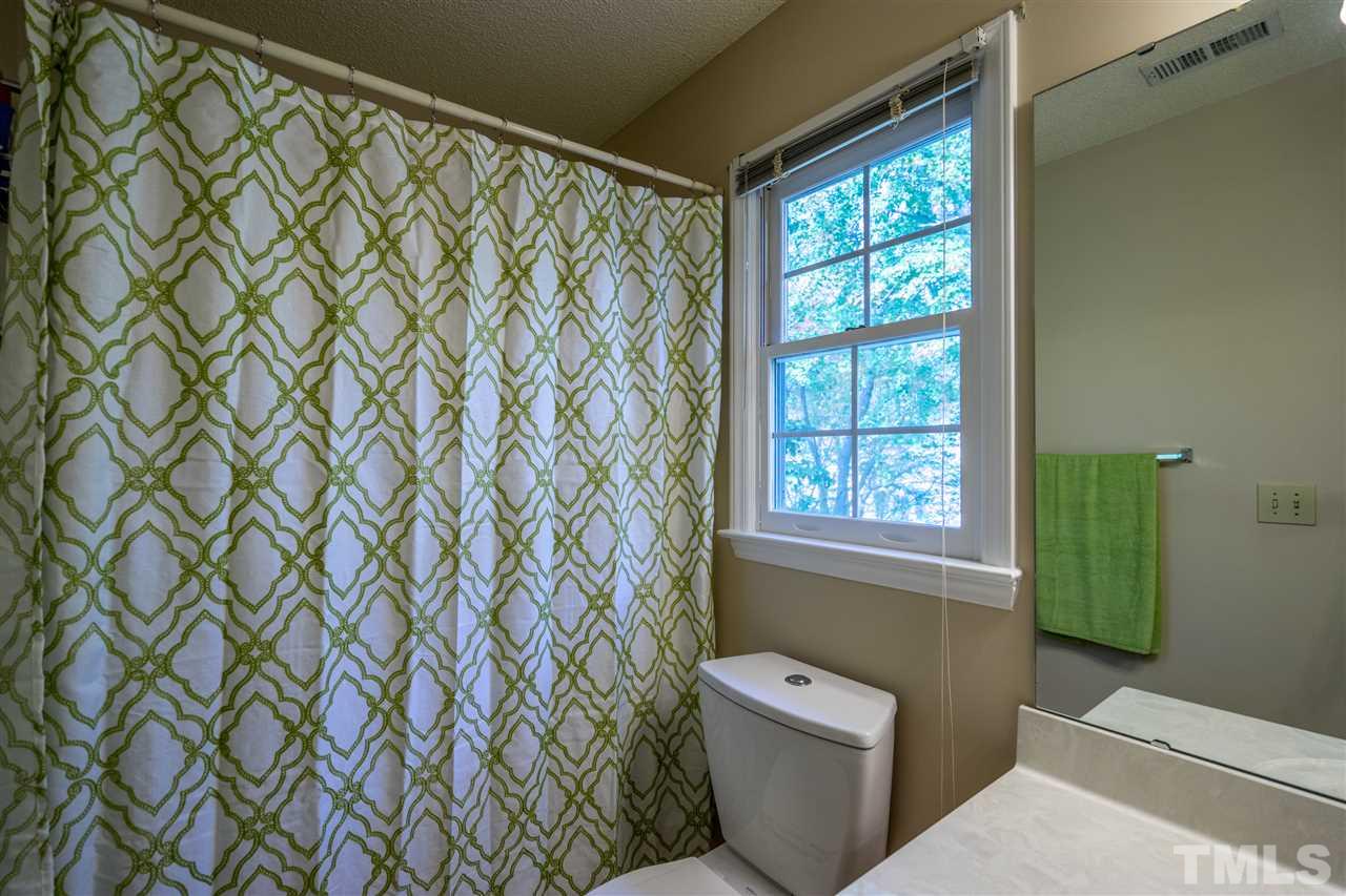 11912 Fairlie Place Raleigh, NC 27613 - Photo 22 of 25 a bathroom with a toilet and a shower curtain