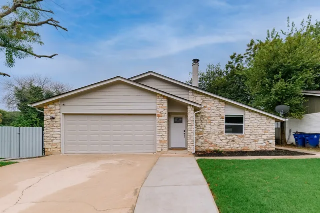 a front view of house with yard and trees in the background