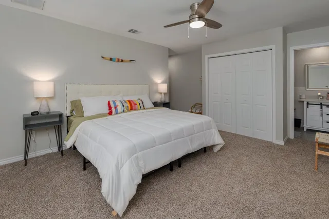 a spacious bedroom with a bed a flat screen tv and a ceiling fan