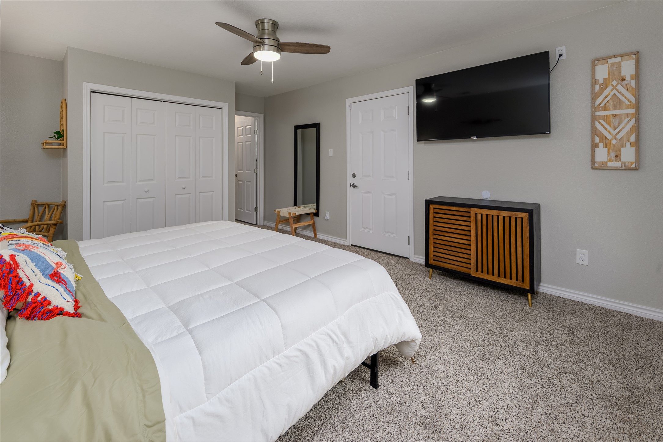 1651 Chippeway Lane Austin, TX 78745 - Photo 16 of 26 a spacious bedroom with a bed a flat screen tv and a ceiling fan