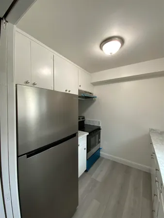 a view of a refrigerator in kitchen and an empty room