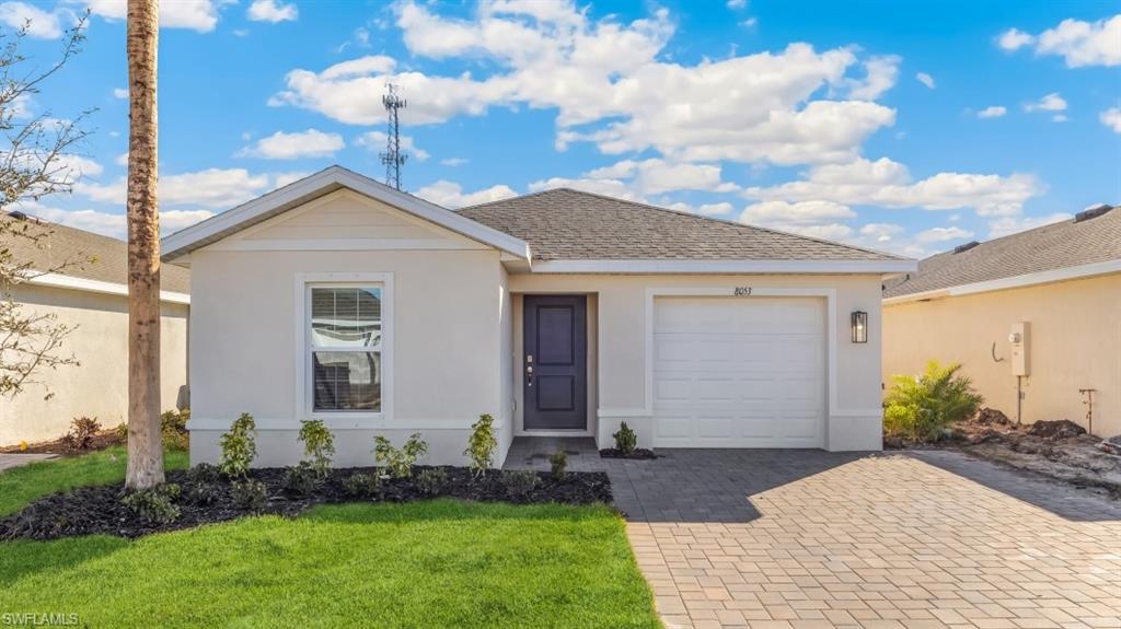 Model home. Ranch-style house featuring decorative driveway, stucco siding, a shingled roof, an attached garage, and a front lawn