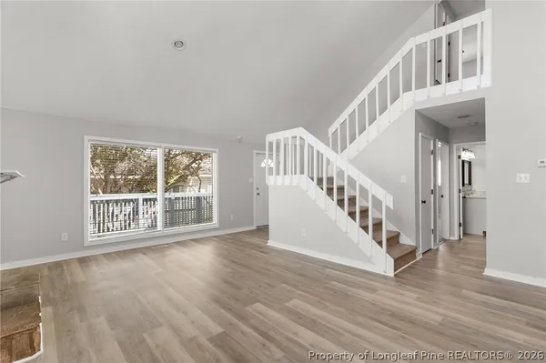 a view of an empty room with wooden floor fireplace and a window
