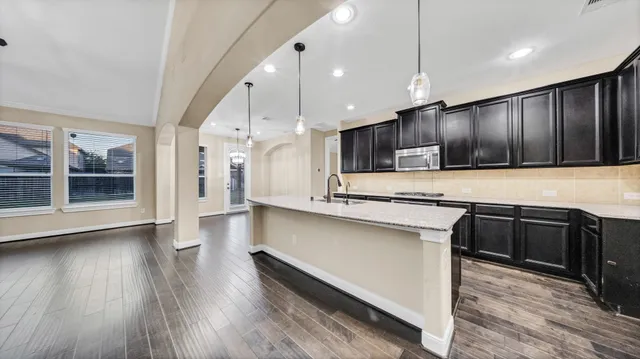 a kitchen with stainless steel appliances granite countertop wooden cabinets a stove a sink and a wooden floors