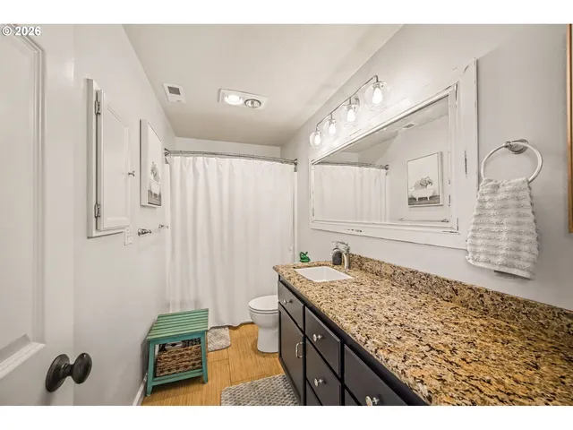 a bathroom with a granite countertop sink a mirror and shower