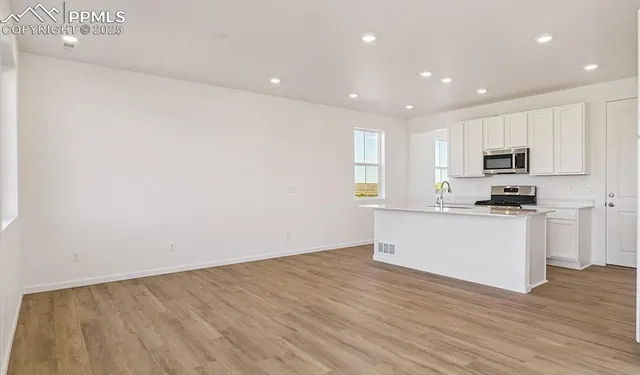 a kitchen with wooden floor white cabinets and stainless steel appliances
