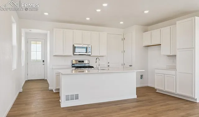 a kitchen with white cabinets and stainless steel appliances