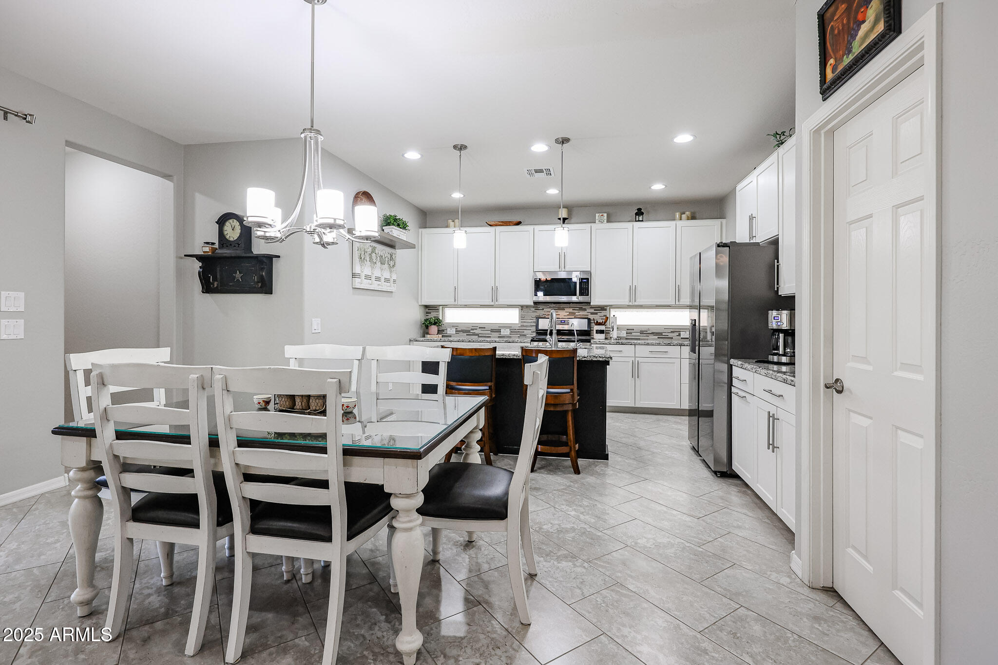 17563 West Fairview Street Goodyear, AZ 85338 - Photo 14 of 66 a kitchen with stainless steel appliances kitchen island granite countertop a dining table chairs and white cabinets