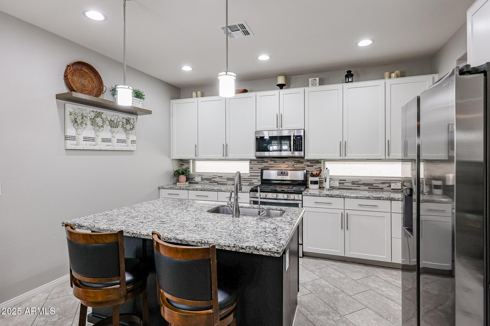17563 West Fairview Street Goodyear, AZ 85338 - Photo 16 of 66 a kitchen with stainless steel appliances granite countertop a table chairs stove and refrigerator