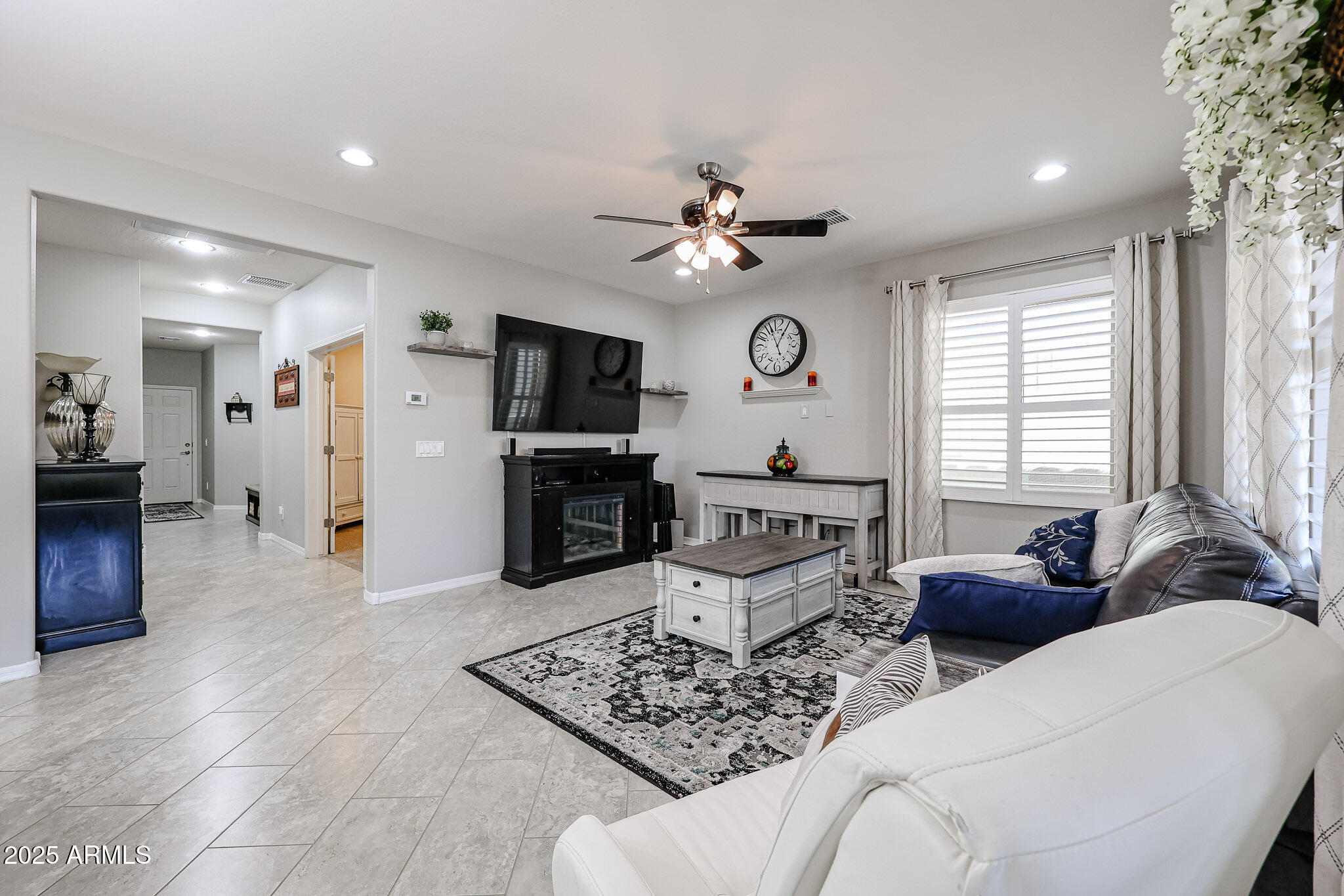 17563 West Fairview Street Goodyear, AZ 85338 - Photo 10 of 66 a living room with furniture a fireplace and a flat screen tv