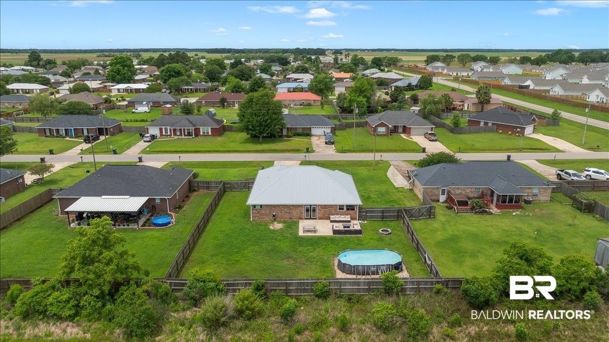 8952 Sherman Road Foley, AL 36535 - Photo 5 of 41 Suburban property featuring an expansive green lawn, wood fence perimeter, and a patio with outdoor seating