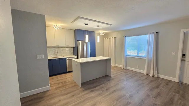a view of a kitchen with wooden floor and electronic appliances