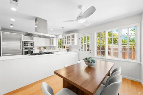 a living room with stainless steel appliances furniture a kitchen view and a large window