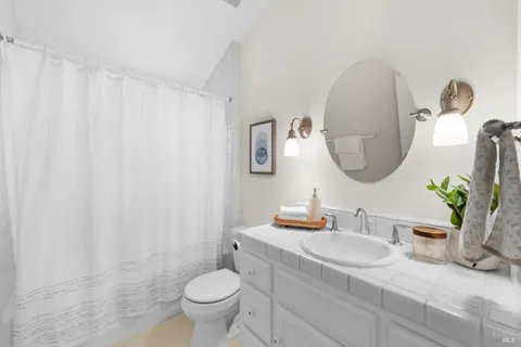 a bathroom with a granite countertop sink mirror and toilet